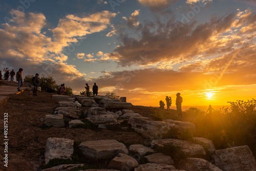 SOUNION, GREECE, 12 DECEMBER 2021: People watching the sunset over the Aegeum Sea in Cape Sounion archaelogical site photo