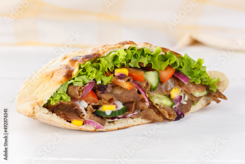Döner Kebab Doner Kebap slice fast food in flatbread on a wooden board