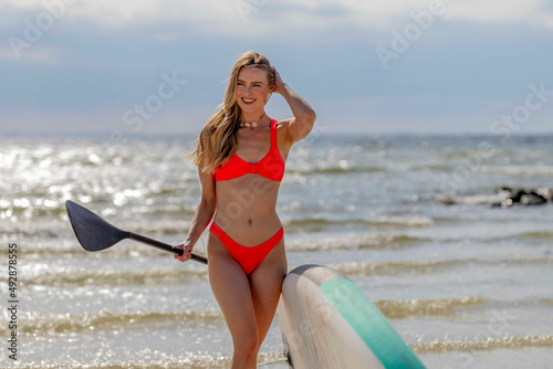 Lovely Blonde Model Enjoying A Summers Day While Preparing To Surf On The Ocean With Her Boogie Board