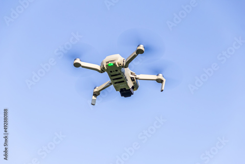 Um drone flutuando no ar com céu azul ao fundo.