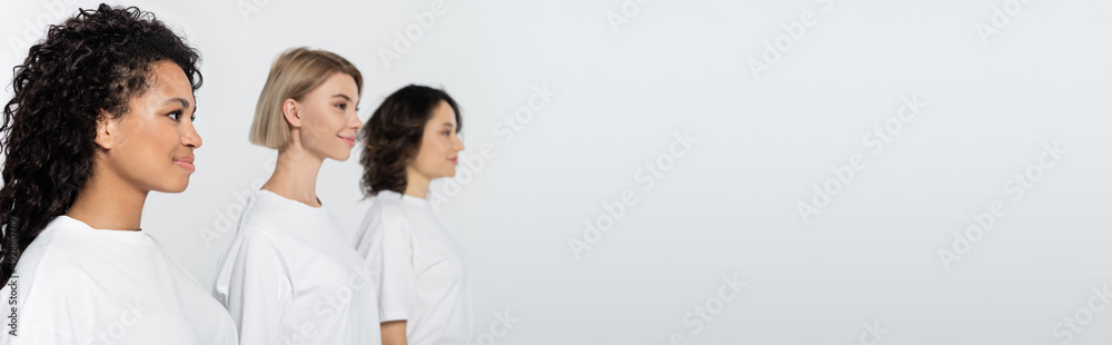 Positive african american woman standing near blurred friends isolated on grey, banner. Positive african american woman standing near blurred friends isolated on grey, banner.