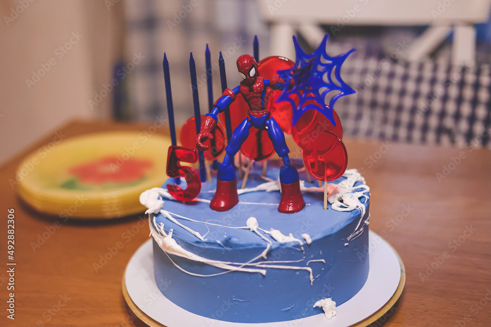 Obraz premium Ivanovo Russia- January 26, 2022: five years old boy's birthday cake decorated with spider man toy, candles and lollipops standing on the table.