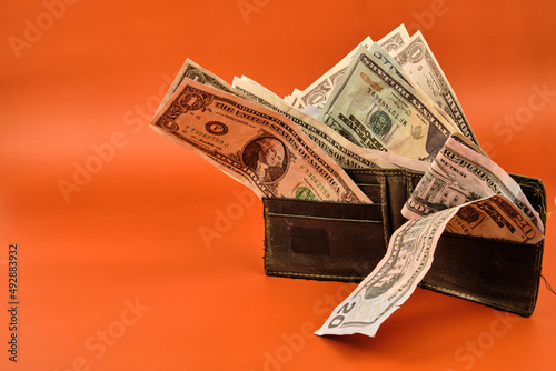 Wallet full of dollars on an orange background