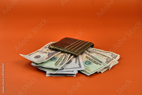 Wallet full of dollars on an orange background. Photography in horizontal format. Copy space.