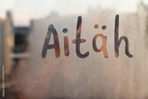 Estonian word Aitah thanks in english are painted on wet orange sunrise glass of window photo