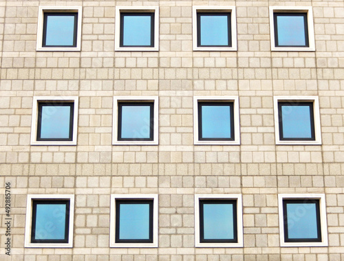 Pattern forms by windows in rows on the exterior block wall of a building. No people.