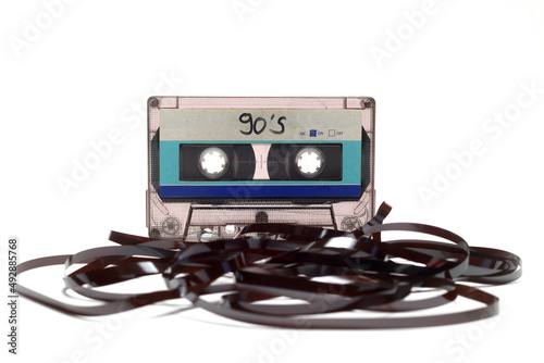 This shows a well known problem with the old fashioned compact cassettes: the tape used to come out, making the cassette useless. Vintage compact cassette tape on white background.