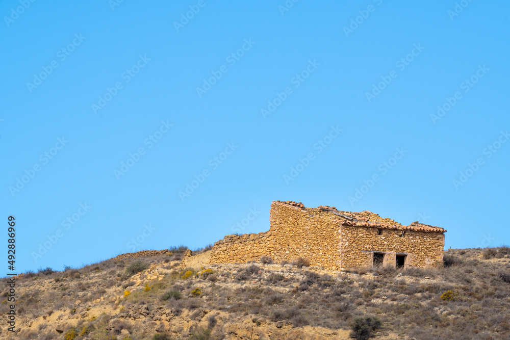 Ruined old spanish country house on scrub hill and blue sky