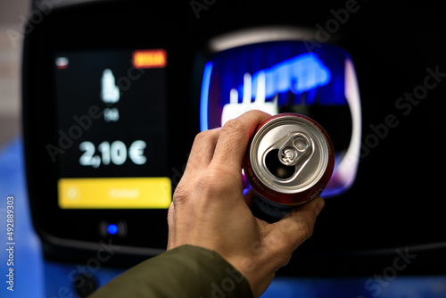 Fotografie recycling a can for cash in a supermarket by throwing it into a recycling machin