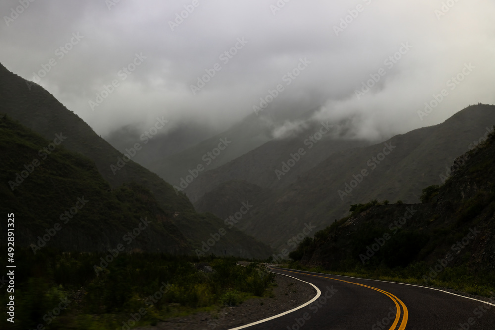 Fototapeta premium Highway between hills with low clouds at dusk in Salta, Argentina