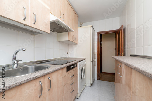 Furnished kitchen with similar pink granite countertop with white appliances and black ceramic hob in a rental apartment