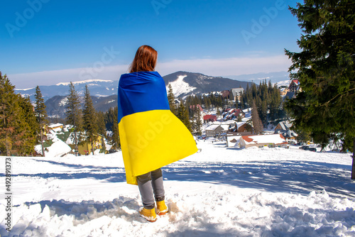 Woman holding,carring ukrainian national blue yellow flag.war,conflict,military invasion beetwen Russia as terrorist aggressive cruel country and Ukraine.Ukraines Independence Flag,Constitution day photo