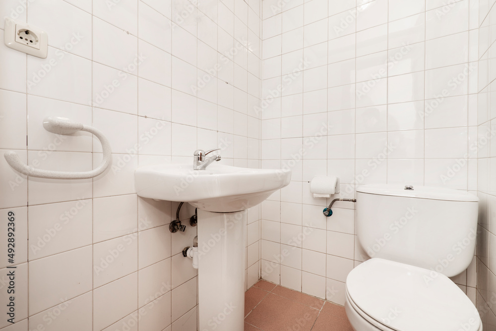 Spartan toilet with square white porcelain tile, sink and toilet