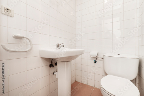 Spartan toilet with square white porcelain tile, sink and toilet