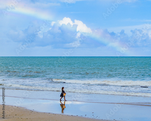 Mulher de vestido caminhando na beira do mar com arco-  ris ao fundo na Praia de Boa Viagem  recife  Pernambuco