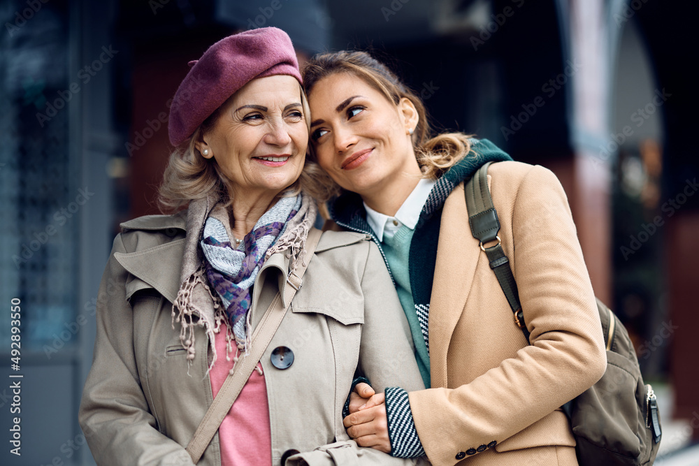 Happy mid adult woman enjoys in time she is spending with her senior mother outdoors.