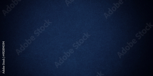 Dark blue background texture with black vignette in old vintage grunge textured border design, dark elegant teal color wall with light spotlight center 