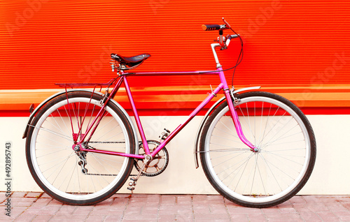 Colorful image retro pink bicycle standing in the city on vivid background