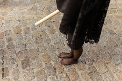 woman dressed in mantilla with a black skirt doing penitential station barefoot. Promise of a barefoot woman with faith in jesus and mary in an holy week procession. Woman with a candle in her hand. photo
