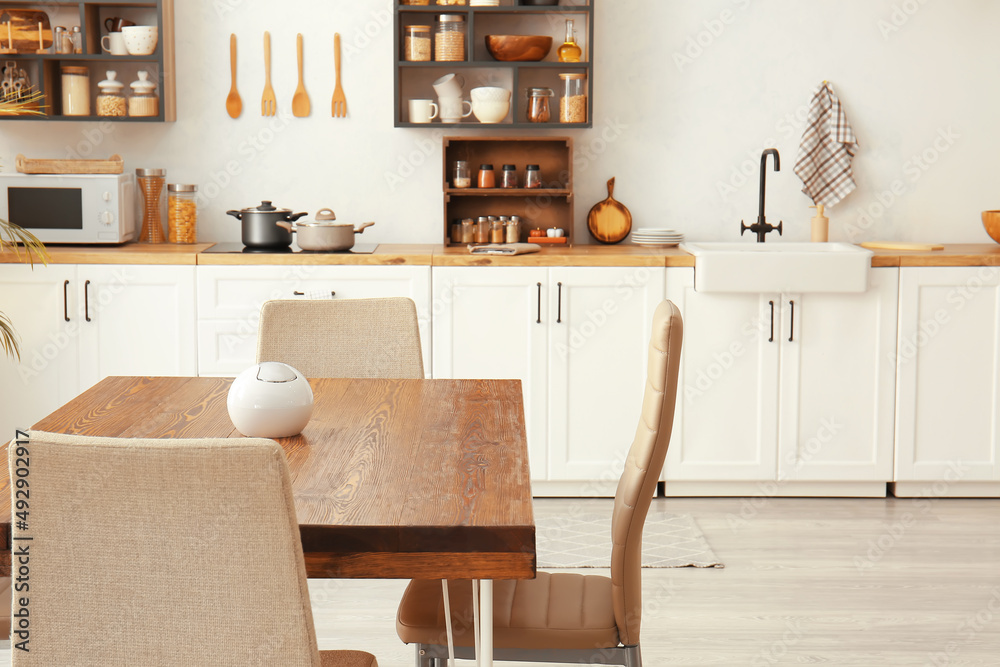 Wooden dining table with chairs in light kitchen Wooden dining table with chairs in light kitchen