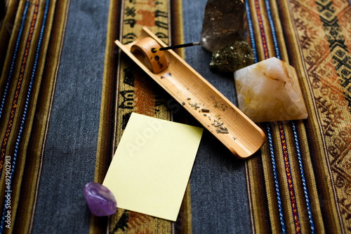 Yellow blank note reminder paper mockup with ethnic background and mystic environment with cristal rocks, incense and plants flowers. Zen message. 