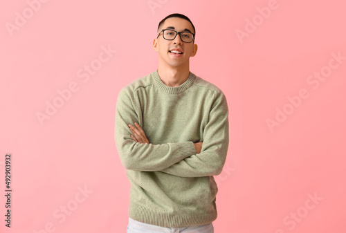 Handsome young Asian man in knitted sweater on pink background