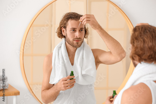Young man using serum for s...