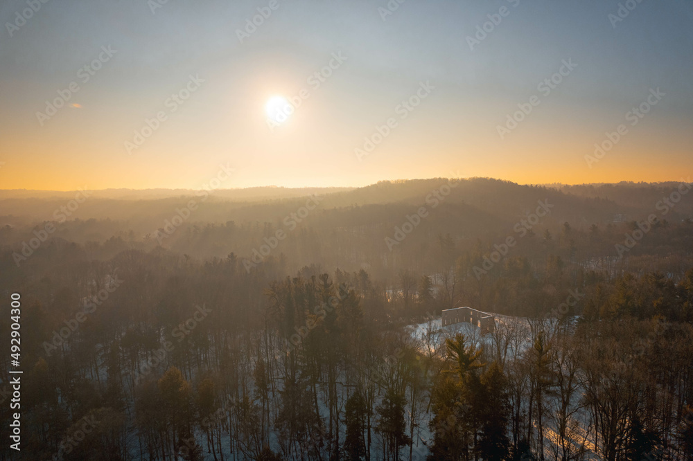 Fototapeta premium An aerial view of a misty sunrise over a forested valley with ruins in winter, in Hamilton, Ontario, Canada.