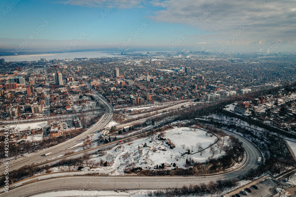 An aerial view of a dense urban cityscape with highways in the bright sunny morning light during winter in Hamilton, Ontario, Canada.