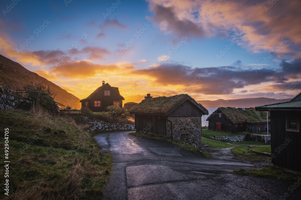 Old log farmhouse of Kirkjuboargardur with turf roof in Kirkjubour village on Streymoy, Faroe Islands. Sunrise time, november 2021