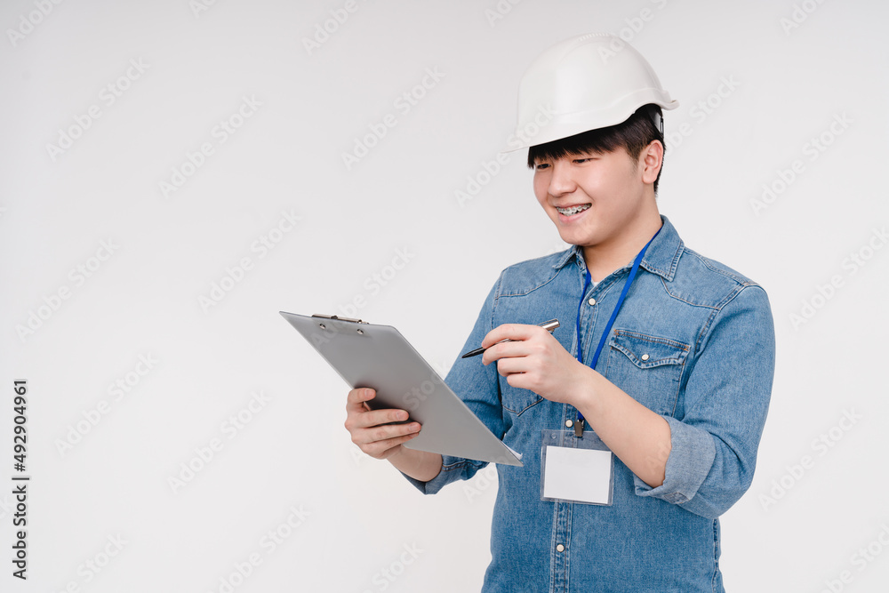 Asian korean young architect construction worker in white hardhat writing checking quality on clipboard isolated in white background Asian korean young architect construction worker in white hardhat writing checking quality on clipboard isolated in white background