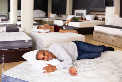 Young man fell asleep on new mattress in a furniture store