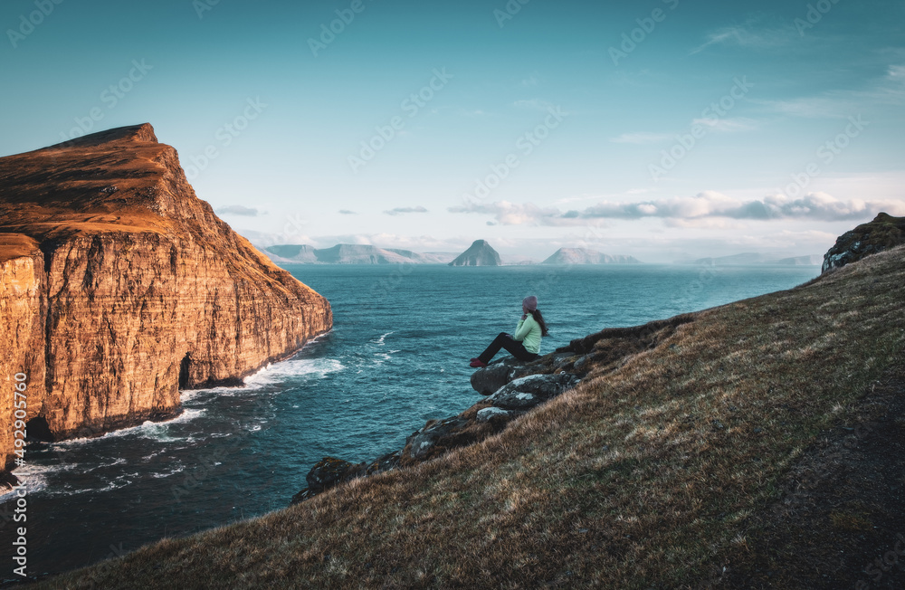 Naklejka premium Faroe Islands Traelanipa the slaves rock cliff is seen rising over the ocean next to lake Sorvagsvatn. Clouds and blue sky during autumn on the island vagar in the Faroe Islands. November 2021