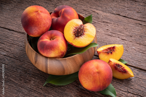 Yellow Peach with slice in wooden basket, Fresh Yellow Peach fruit in wooden bowl on wooden background. photo