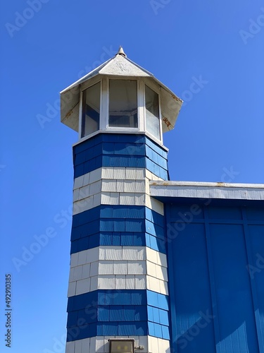 Blue and white wooden lighthouse on the sea close up 