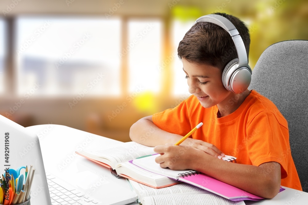 School child learning at Home. Headset study from home look. School age child engaged in learning on distance listen to teacher at online lesson School child learning at Home. Headset study from home look. School age child engaged in learning on distance listen to teacher at online lesson