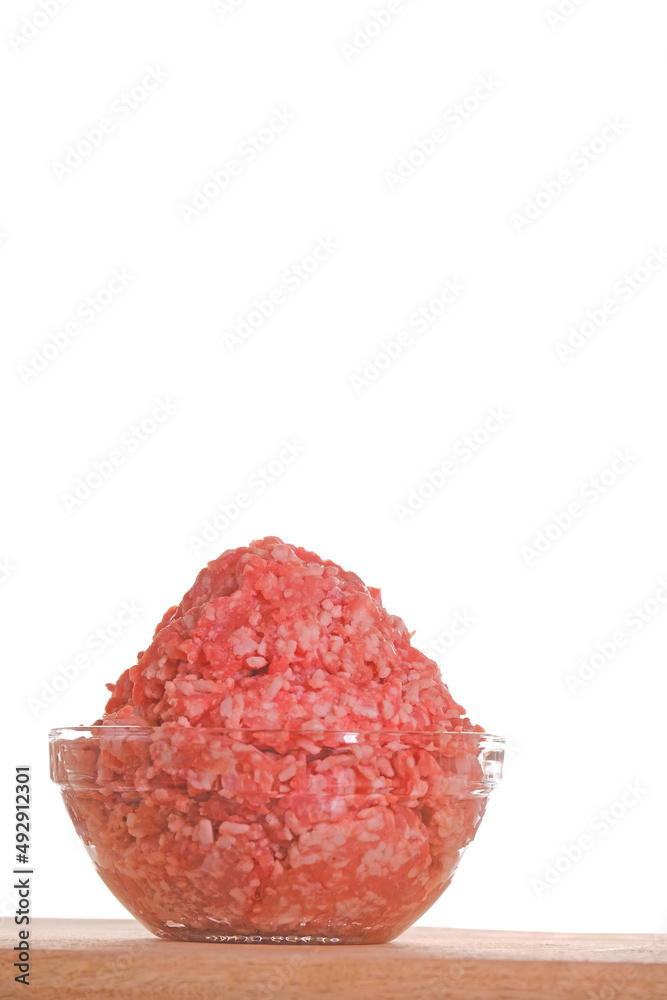 minced pork. fresh raw minced meat close-up in a transparent cup on a wooden table isolated on white background.Minced meat texture.Meat products.Ground fresh meat close-up. minced pork. fresh raw minced meat close-up in a transparent cup on a wooden table isolated on white background.Minced meat texture.Meat products.Ground fresh meat close-up.