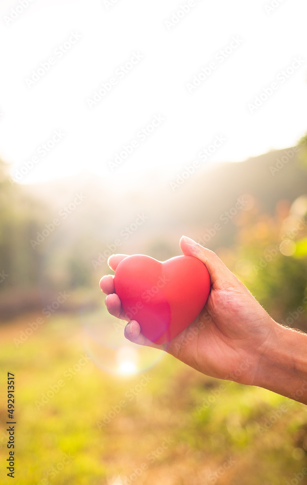 Hand holding heart against a golden sunset. Hand holding heart against a golden sunset.