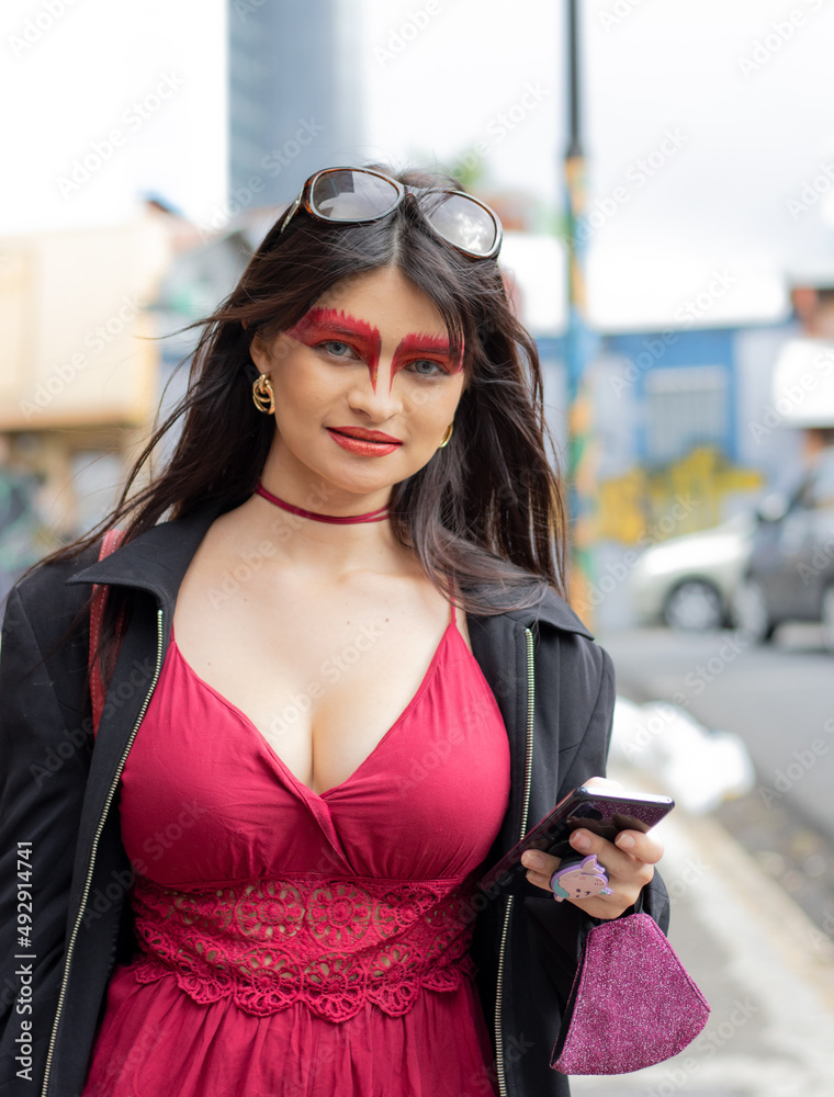 Latin woman with fantasy makeup in red color, with red dress, LGTBI, freedom of expression, empowered woman. blur background, copy space background, woman urban photo in San Jose Costa Rica. 
