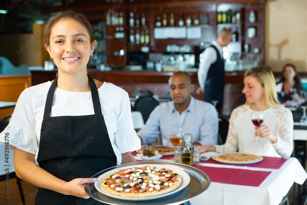Portrait of smiling waitress with serving tray pizza at a restaurant