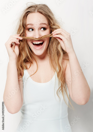 Having fun. Playful young woman making a mustache with her hair against a white background.