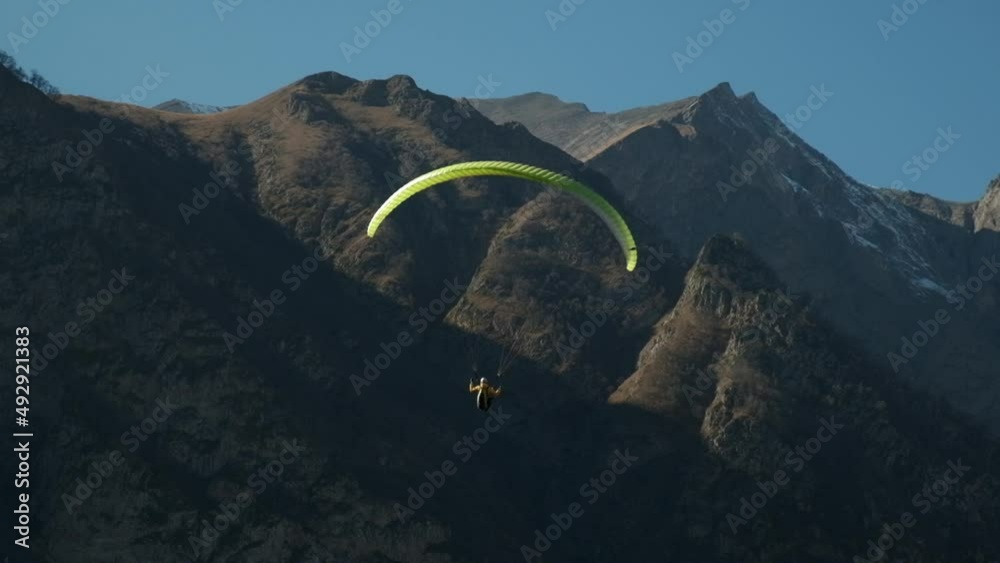a lot of paragliders fly in the mountains, a bunch of paragliders hover over the rocks