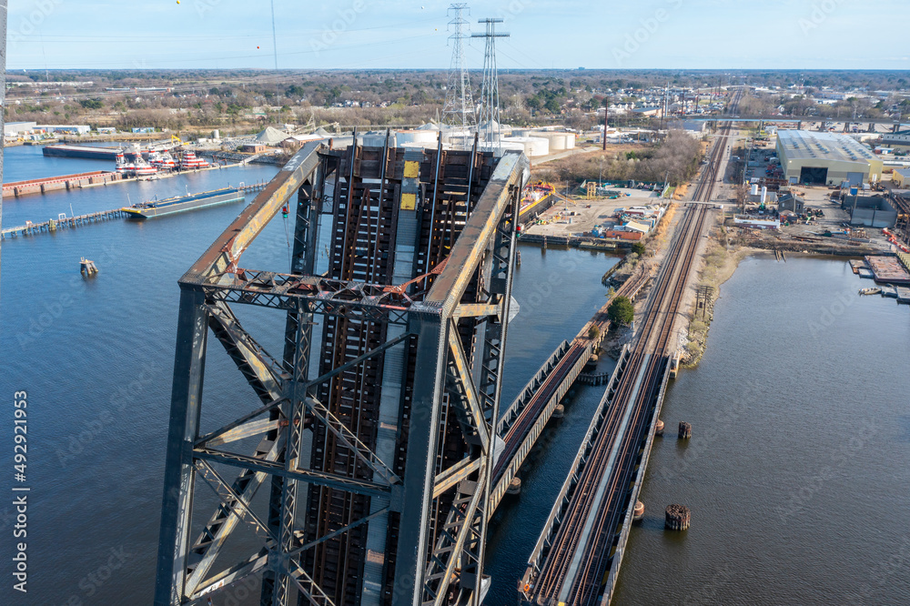 Aerial view of a railroad Draw bridge in the vertical lift position with the rail line extending off in the distance