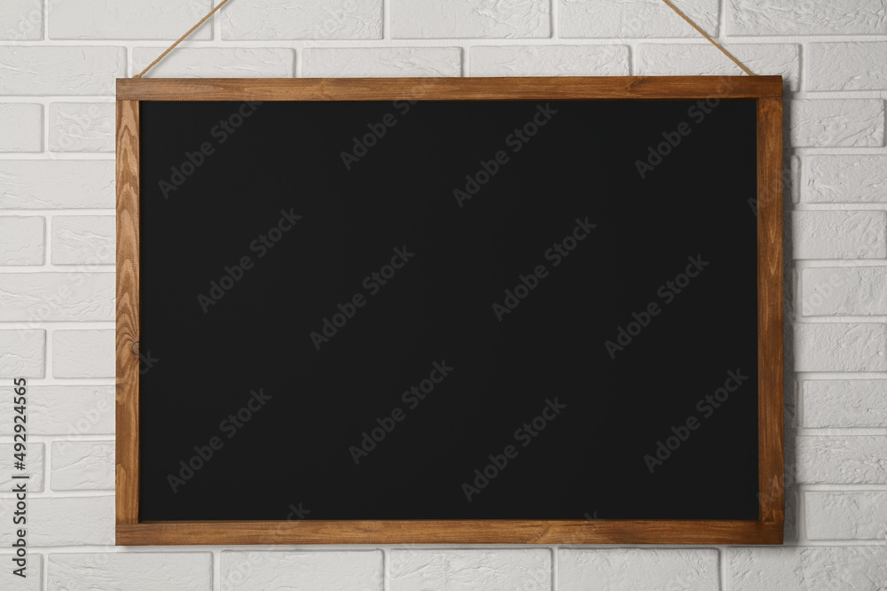 Clean black chalkboard hanging on white brick wall Clean black chalkboard hanging on white brick wall