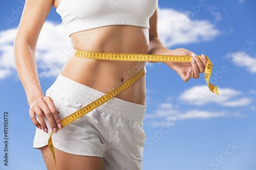 Concept diet. Woman measures her waistline with measuring tape. Healthy body shaping weight loss concept.