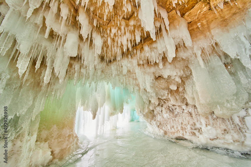 Ice cavern on frozen lake with ceiling covered in small icicles