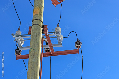 High-voltage disconnector on a wooden power line support on a blue sky background