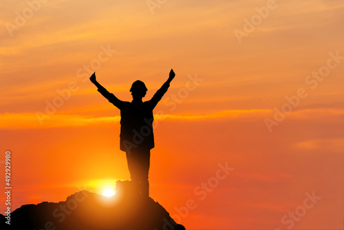 Silhouette of man in hard hat with clipping path celebration success on a mountain top sunset sky background