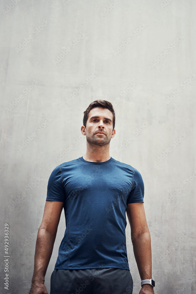 The impossible is merely in your mind. Shot of a sporty young man standing against a grey wall while exercising outdoors. The impossible is merely in your mind. Shot of a sporty young man standing against a grey wall while exercising outdoors.