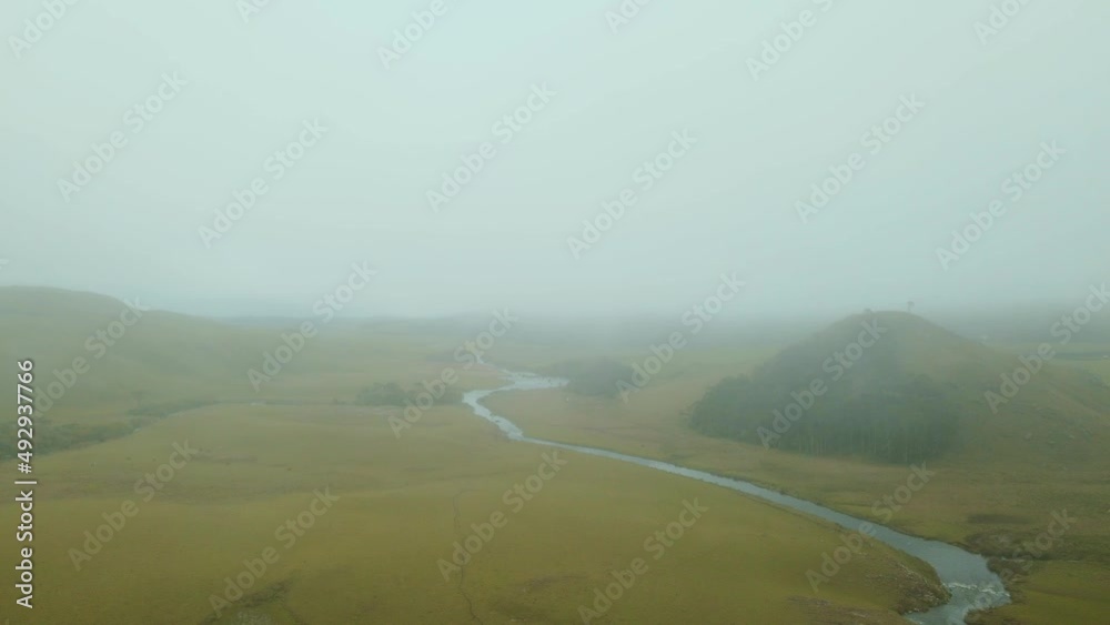 Aerial View of a Green Field with River and some Hills in Foggy Day. Aerial View of a Green Field with River and some Hills in Foggy Day.